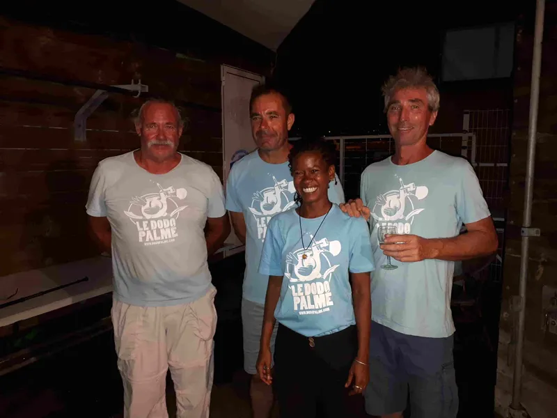 Quatre personnes souriantes posent devant un mur clair et sombre
