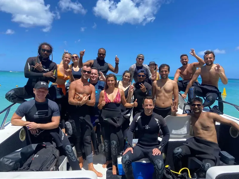 Groupe de plongeurs souriants sur un bateau en mer turquoise