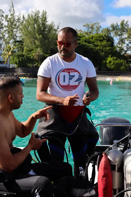 Deux plongeurs discutent près d'un bateau sur une eau turquoise