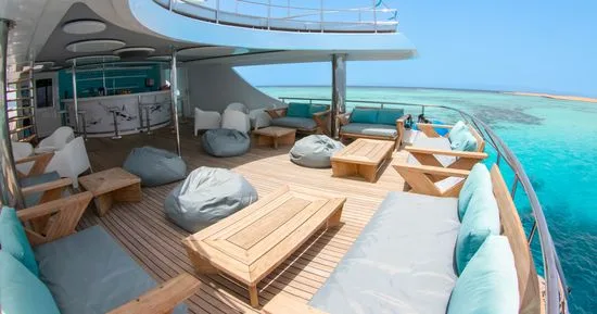 Terrasse en bois d'un bateau de plongée avec mobilier confortable et vue mer