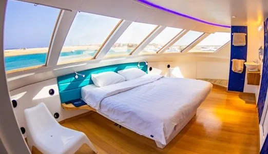 Intérieur lumineux d'une cabine de bateau avec un grand lit et vue mer