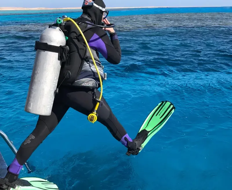 Plongeur équipé se prépare à sauter dans une mer bleue