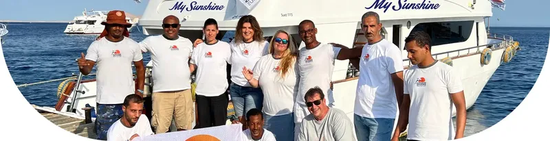 Equipe souriante posant devant un bateau de plongée en mer