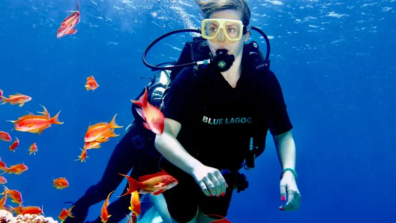 Plongeuse entourée de poissons rouges dans une eau bleue claire