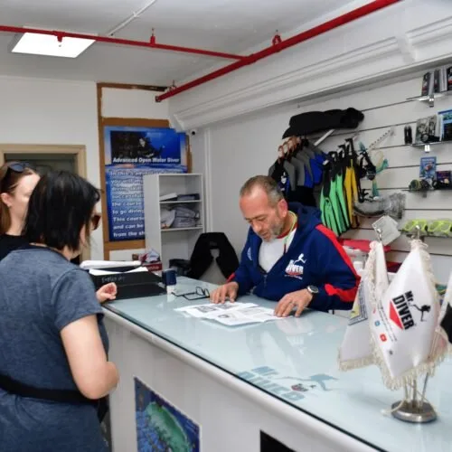 Employé de centre de plongée discutant avec des clientes au comptoir
