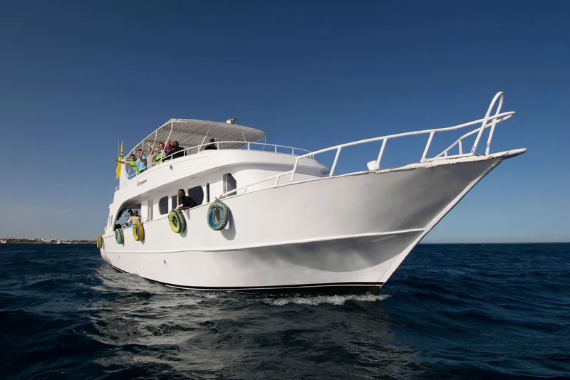 Bateau de plongée blanc en mer avec des passagers souriants