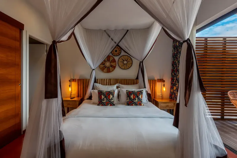 Chambre avec lit à baldaquin, décoration ethnique et éclairage chaleureux