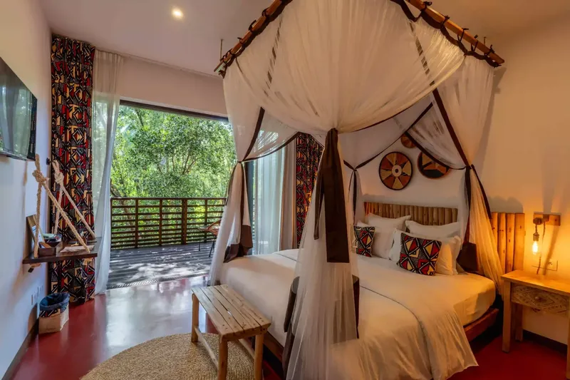 Chambre d'hôtel avec lit à baldaquin et décoration africaine