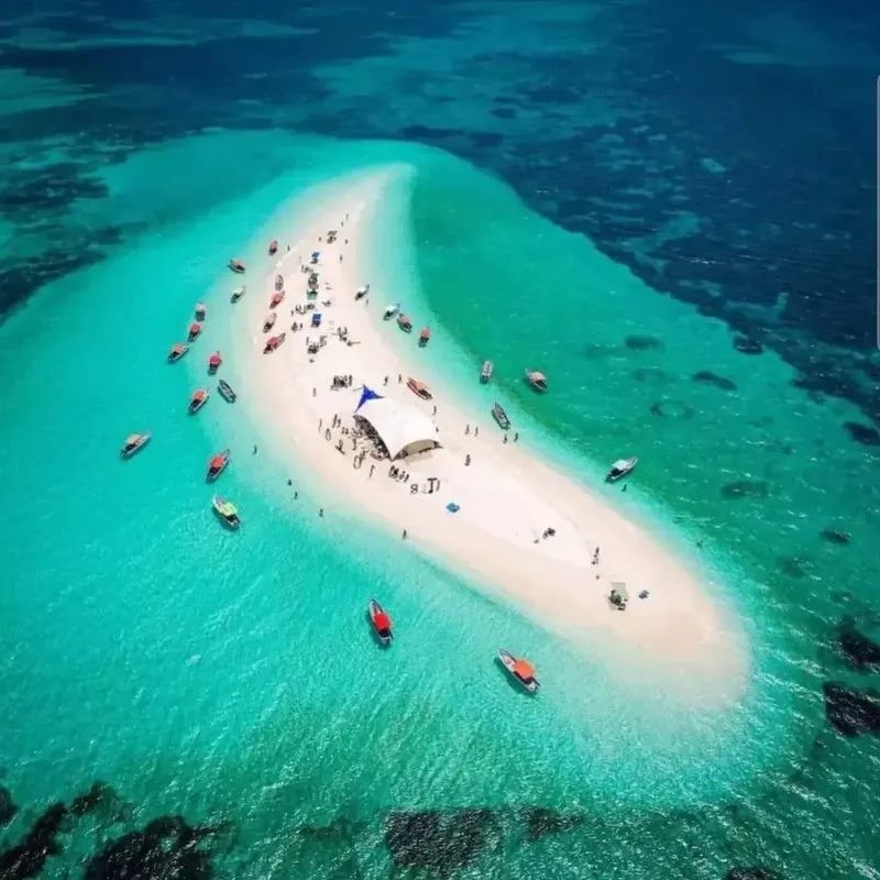 Vue aérienne d'une plage avec des personnes et des bateaux turquoise