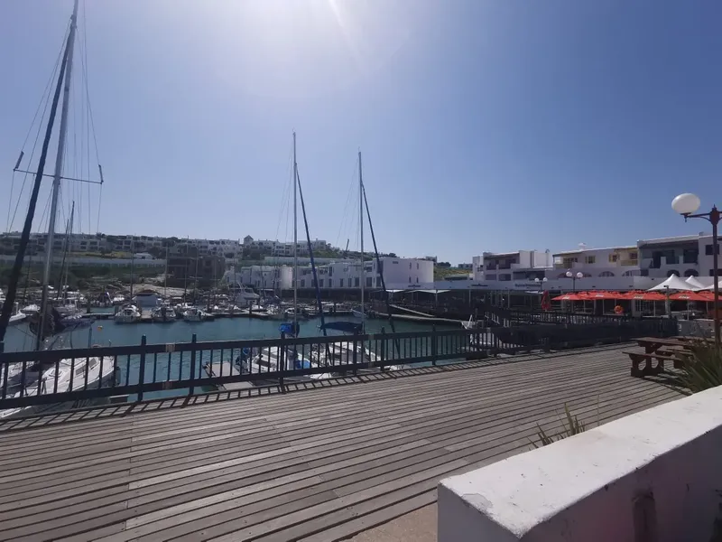 Port de plaisance ensoleillé avec bateaux à quai et bâtiments blancs
