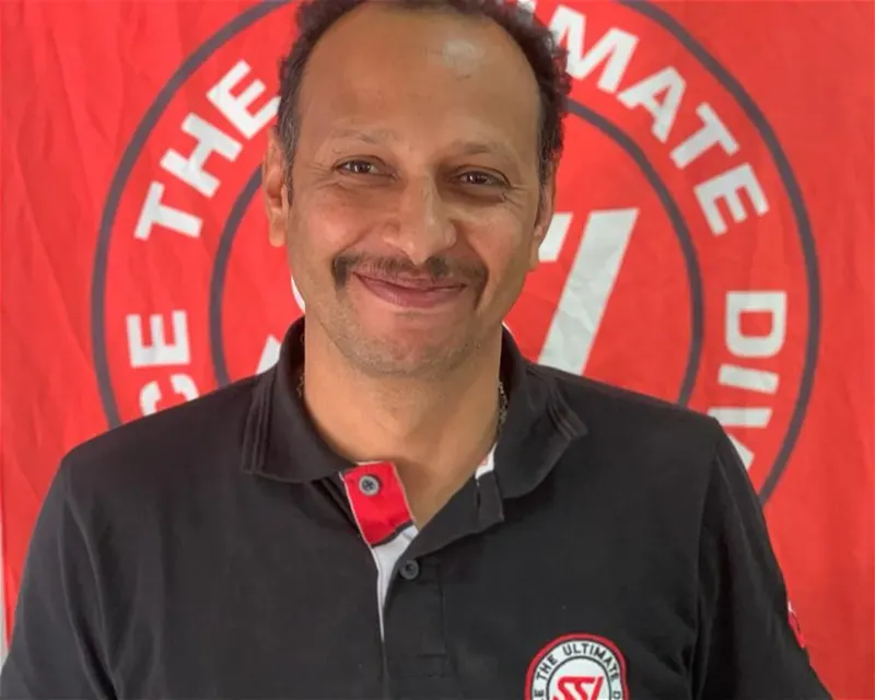 Portrait d'un homme souriant avec un polo et un fond rouge