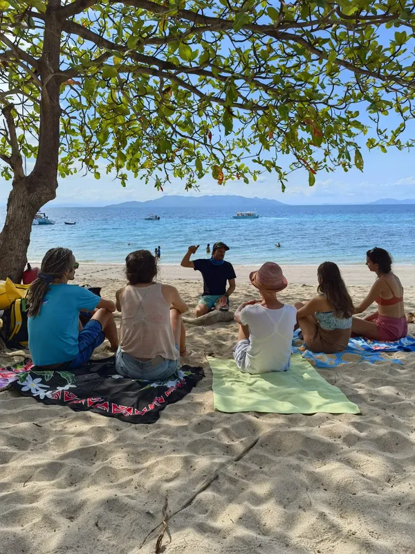 Groupe de personnes sur une plage, un instructeur explique un briefing