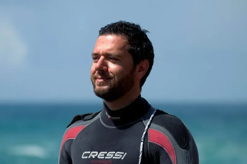 Portrait d'un homme souriant portant une combinaison de plongée noire