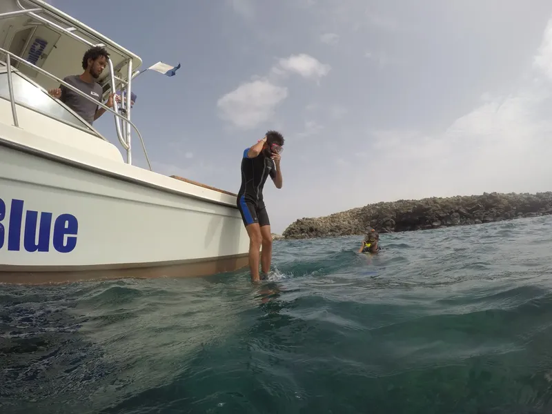 Plongeur s'apprête à entrer dans l'eau depuis un bateau blanc