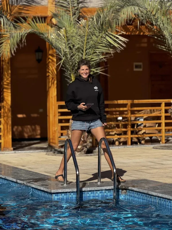 Femme souriante sortant d'une piscine devant un bâtiment en bois