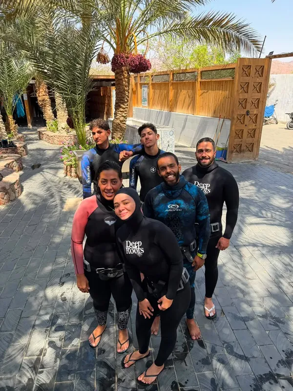 Groupe de plongeurs souriants en combinaison sur un sol pavé