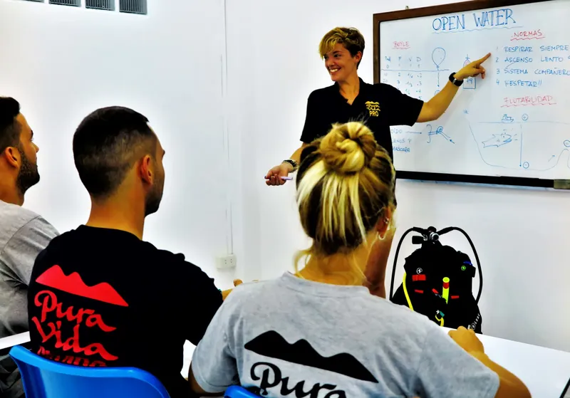 Cours de plongée en salle avec une instructrice expliquant un schéma
