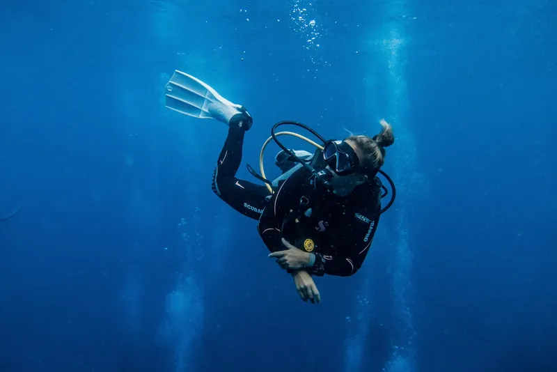 Plongeuse en combinaison noire nageant dans une eau bleue claire