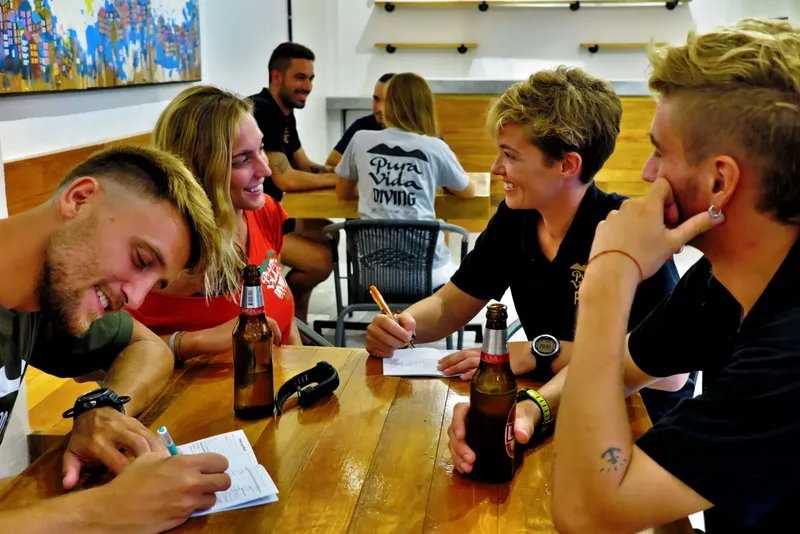 Groupe de personnes souriantes autour d'une table en bois avec des boissons