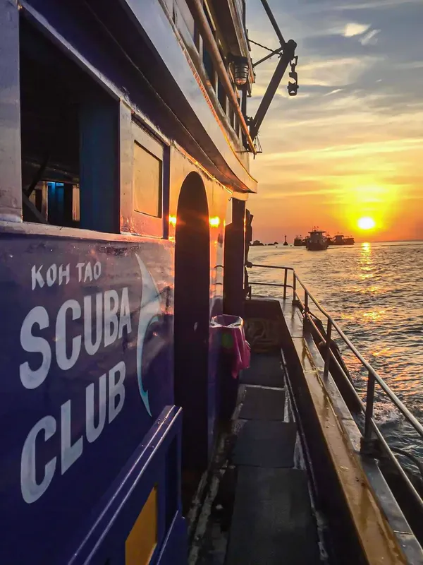 Bateau de plongée avec le nom du club et un coucher de soleil