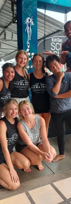 Groupe de jeunes adultes souriants devant un mur décoré et un panneau
