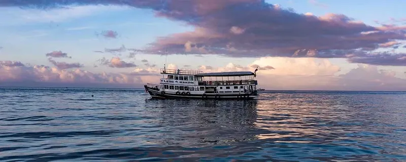 Grand bateau de plongée blanc sur une mer calme au coucher du soleil