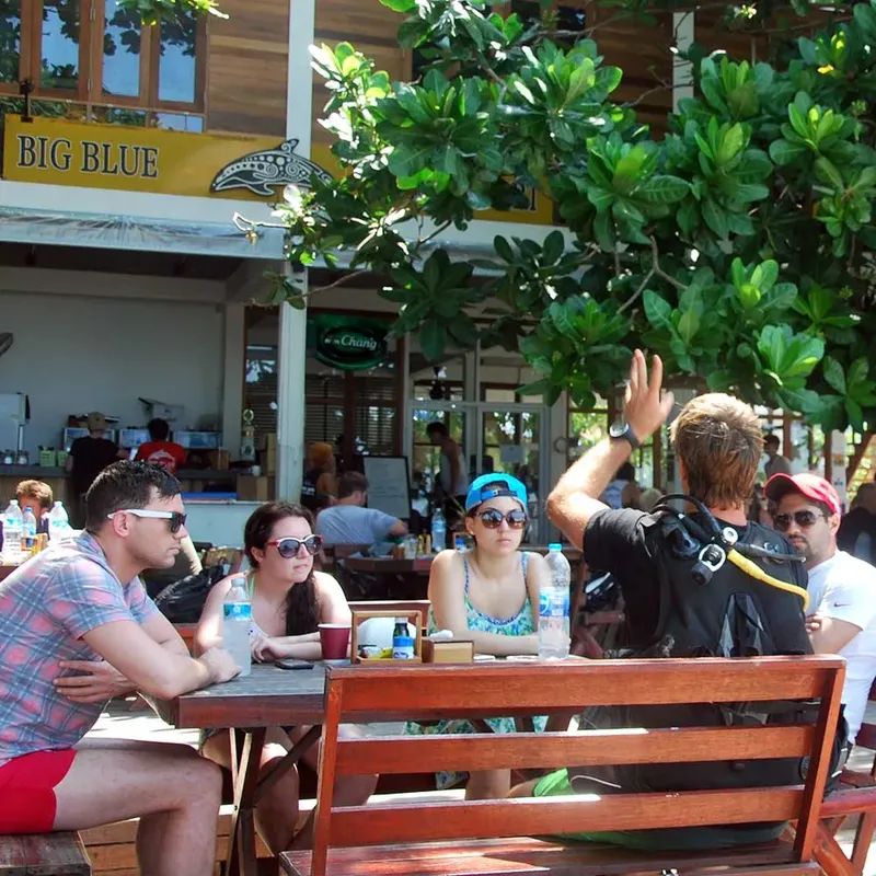 Terrasse d'un centre de plongée avec des clients et une enseigne