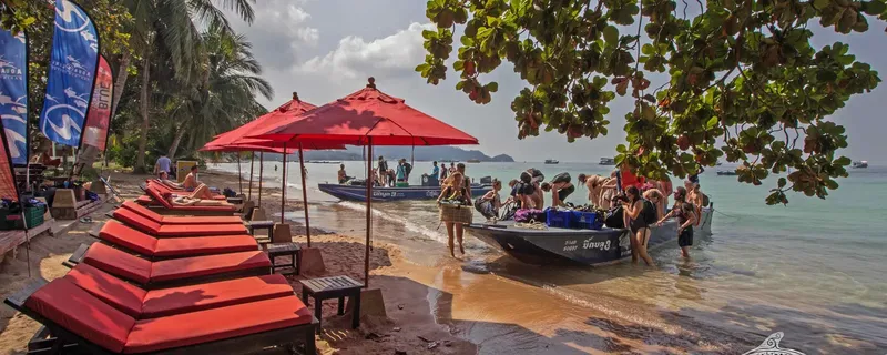 Plage tropicale avec des plongeurs montant à bord de bateaux pneumatiques