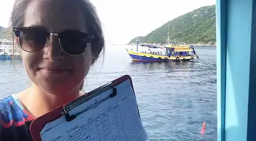 Femme souriante tenant un dossier sur un bateau en mer