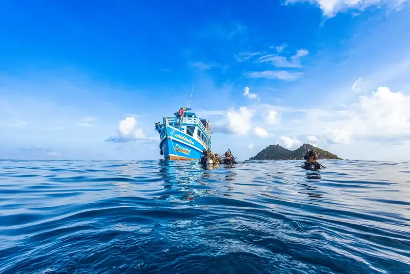 Plongeurs près d'un bateau bleu sur une mer calme et ensoleillée