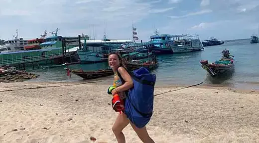 Jeune femme marchant sur une plage avec son équipement de plongée