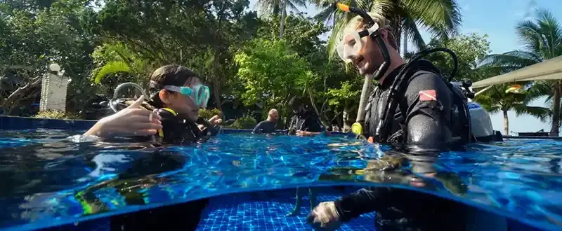 Plongée en piscine, instructeur vérifiant l'équipement d'un élève