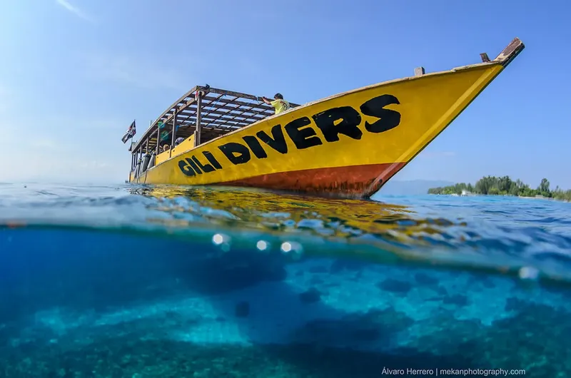 Bateau de plongée jaune et bleu, vue mi-immergée, personnes à bord