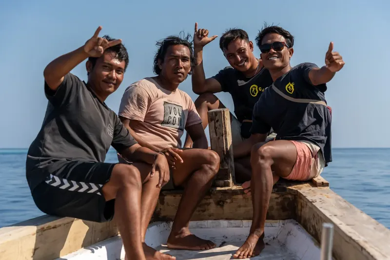 Quatre hommes souriants à bord d'un petit bateau en mer