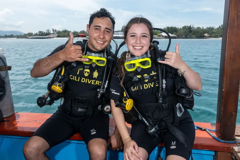 Deux plongeurs souriants avec leur équipement sur un bateau en mer