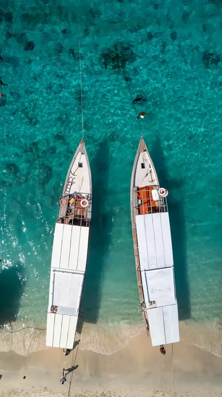 Vue aérienne de deux bateaux de plongée amarrés dans une eau turquoise