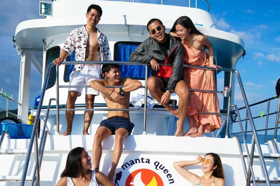 Groupe de personnes souriantes sur le pont d'un bateau de plongée