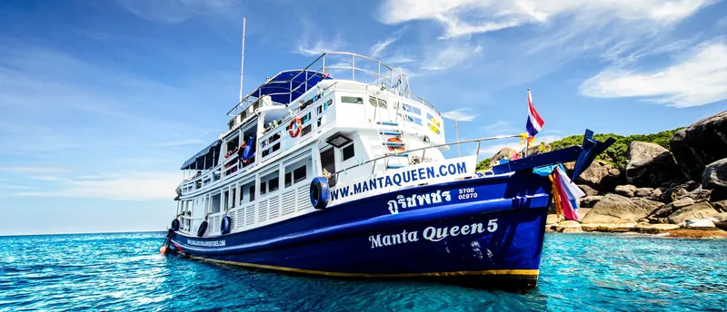 Grand bateau de plongée bleu et blanc navigue sur une mer turquoise