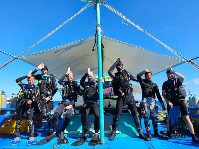 Groupe de plongeurs souriants sur le pont d'un bateau de plongée