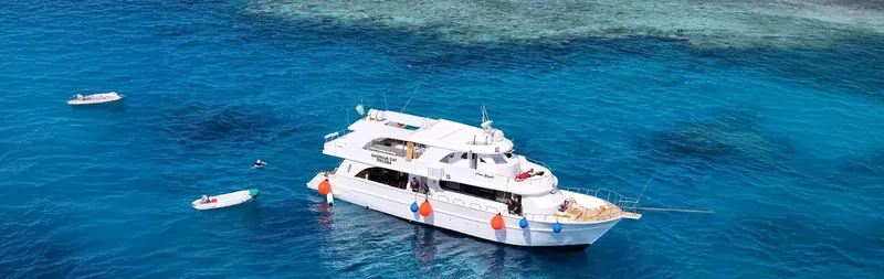 Bateau de plongée blanc sur mer bleue, avec deux petits bateaux