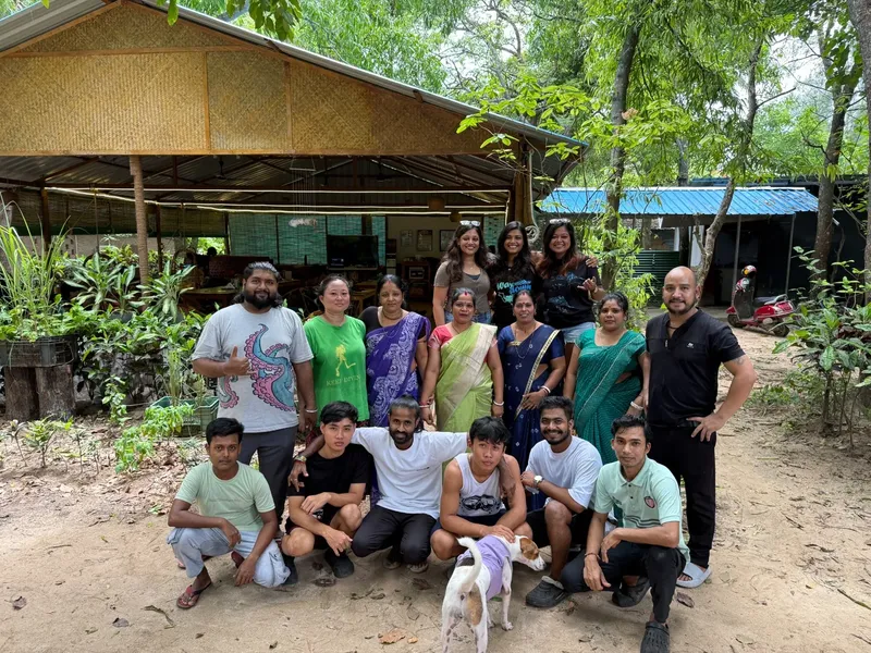 Groupe de personnes souriantes posant devant une structure en bois et végétation