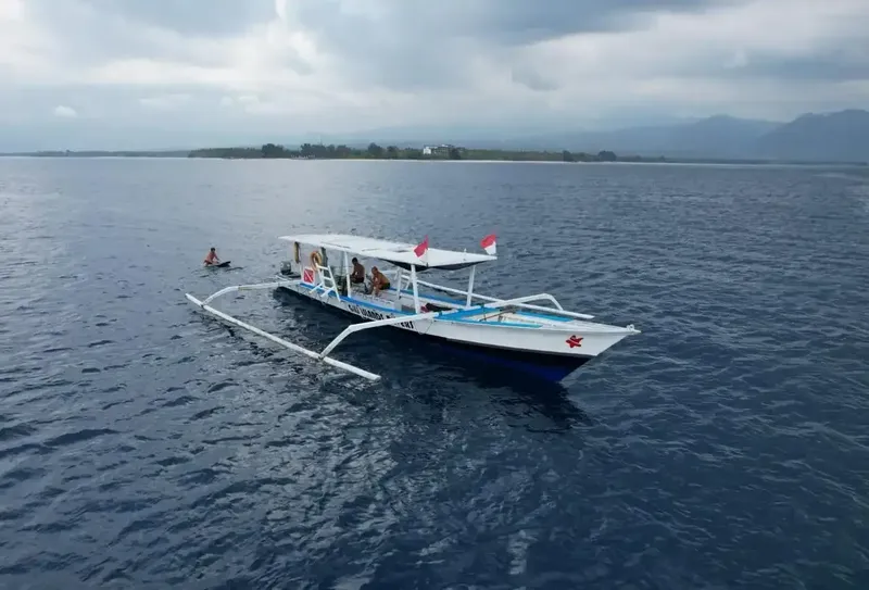 Bateau de plongée blanc avec passagers, mer calme, ciel nuageux