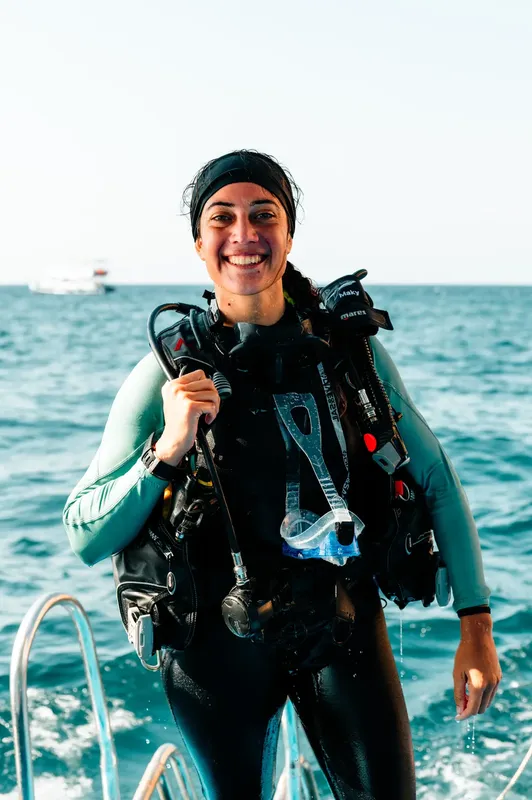 Plongeuse souriante avec son équipement complet sur un bateau en mer
