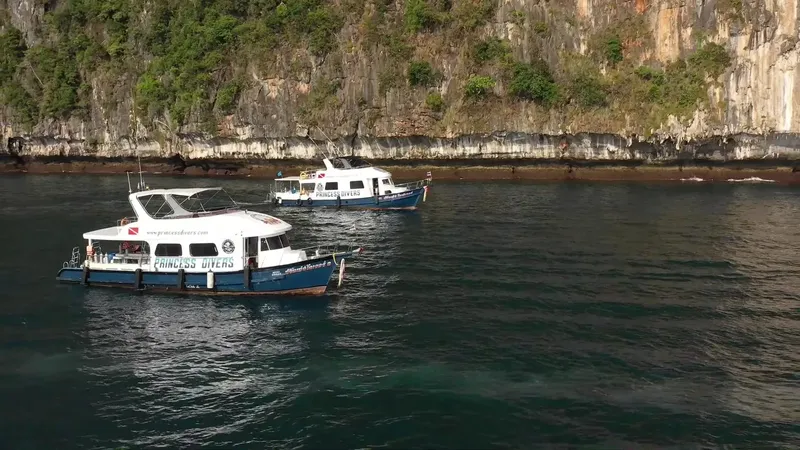 Deux bateaux de plongée amarrés dans une baie rocheuse ensoleillée