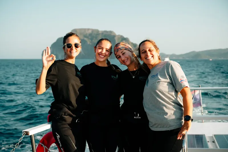 Quatre femmes souriantes sur un bateau en mer, journée ensoleillée