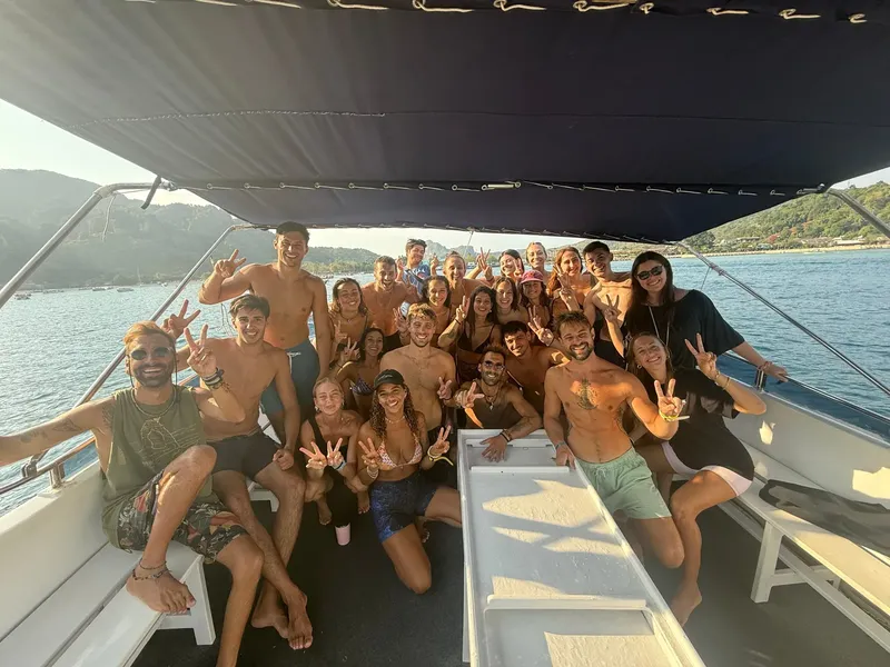 Groupe de personnes souriantes sur un bateau en mer, signe de la paix