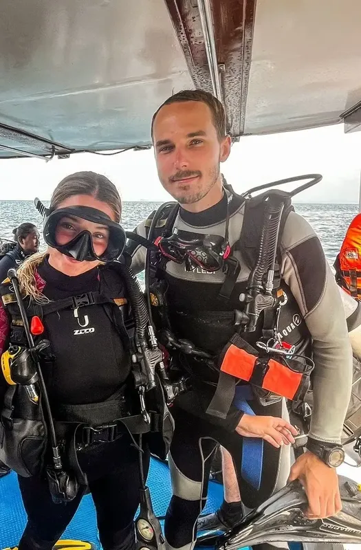 Deux plongeurs souriants équipés sur un bateau en mer