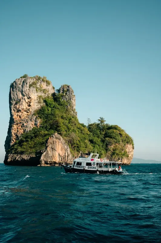 Bateau de plongée au large d'une île rocheuse couverte de végétation