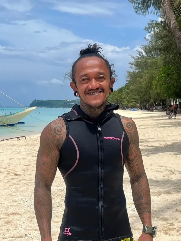 Homme souriant portant un gilet de plongée sur une plage ensoleillée