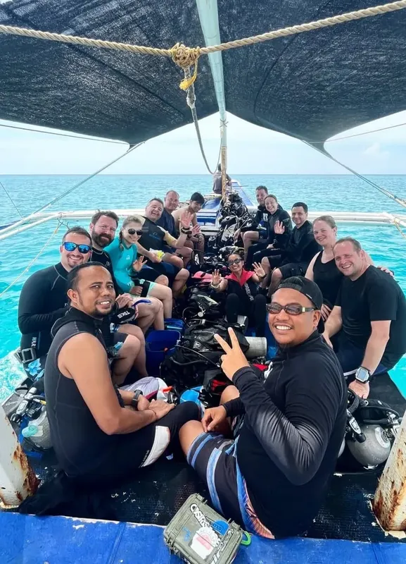 Groupe de plongeurs souriants sur un bateau en mer, prêts à plonger